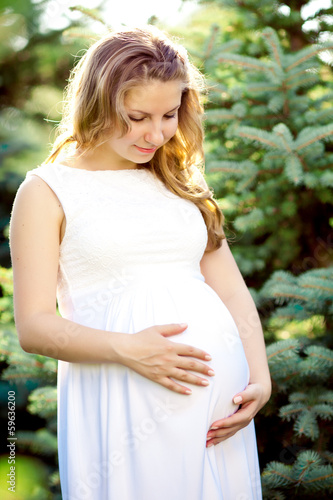 Young healthy beauty pregnant woman outdoors. A girl with a tumm