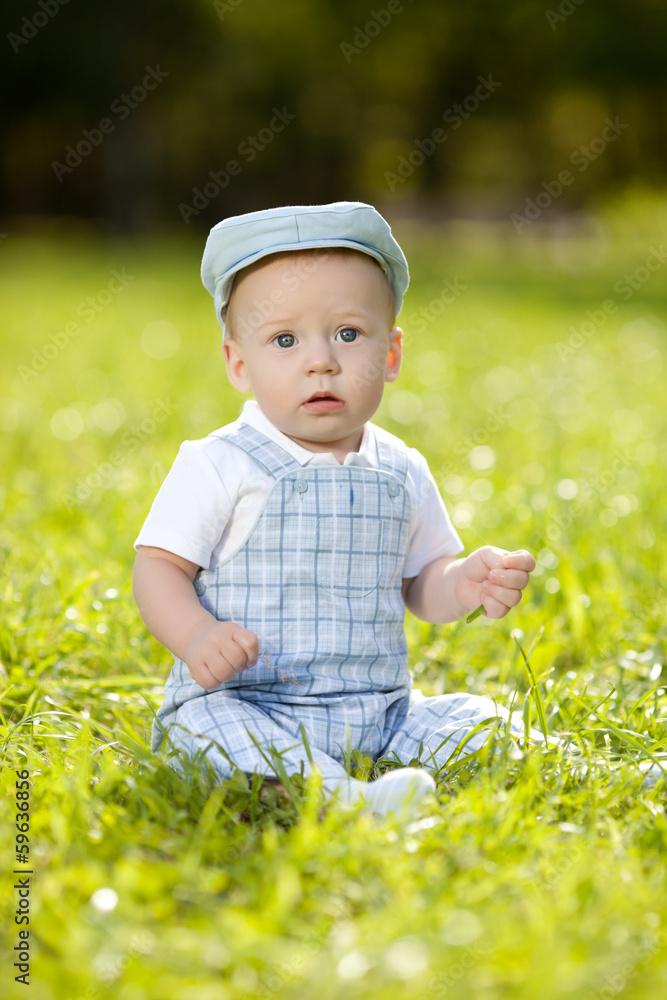 Cute little baby in summer park on the grass. Sweet baby outdoo Cute little baby in summer park on the grass. Sweet baby outdoo