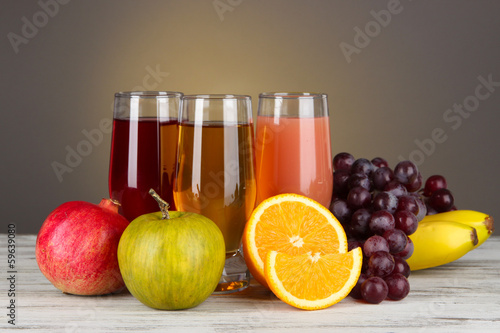 Glasses of fresh juice on table on gray background