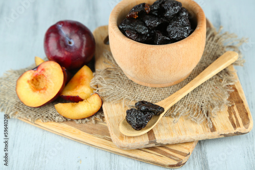Fresh and dried plums in wooden bowl