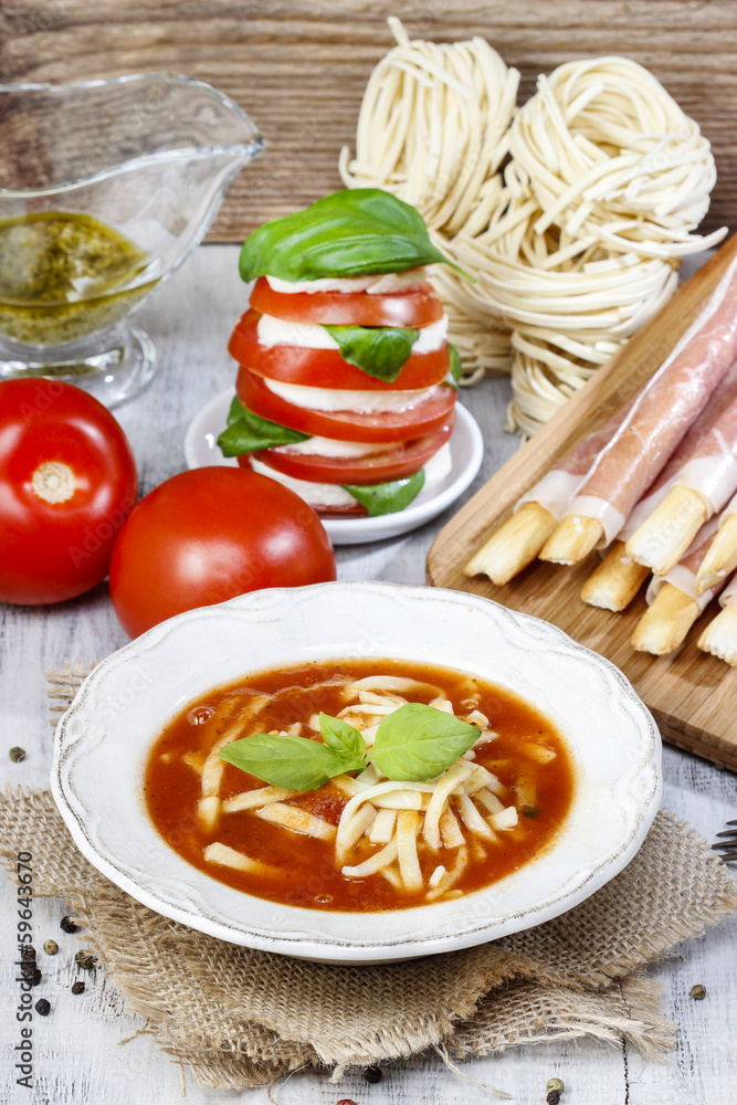 Italian cuisine: tomato soup, breadsticks with ham, caprese sala Italian cuisine: tomato soup, breadsticks with ham, caprese sala