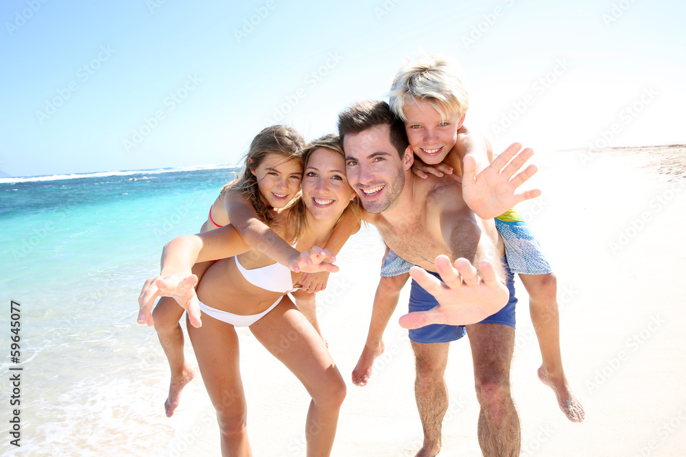 Parents giving piggyback ride to kids at the beach