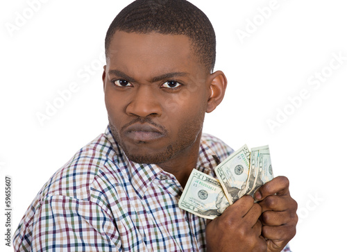 Tableau sur toile Closeup portrait of greedy man  holding dollar banknotes tightly
