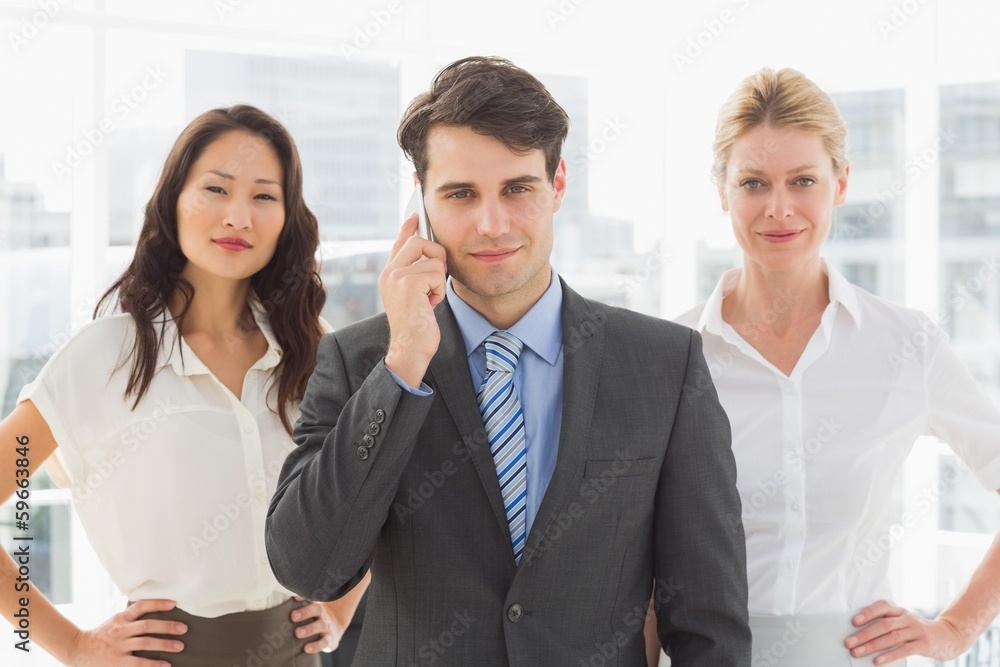 Smiling businessman on the phone in front of his team Smiling businessman on the phone in front of his team