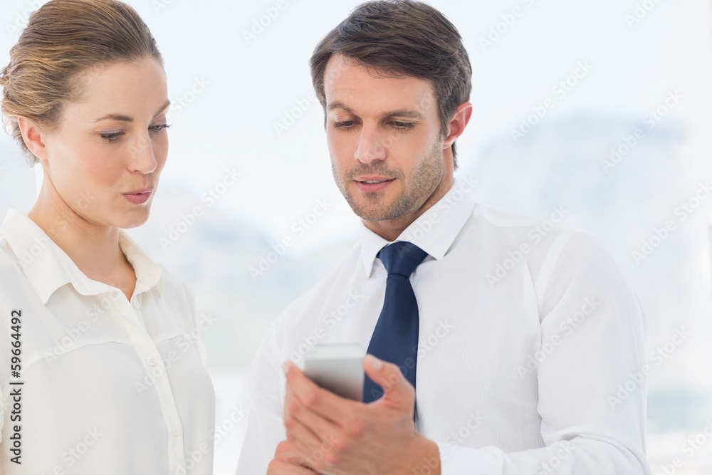 Smartly dressed colleagues looking at mobile phone Smartly dressed colleagues looking at mobile phone