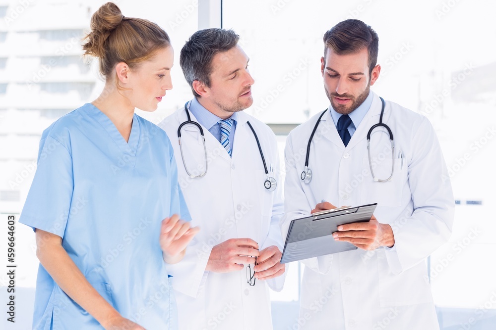 Doctors and female surgeon reading medical reports Doctors and female surgeon reading medical reports