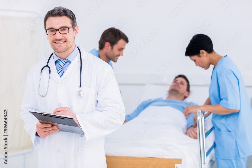Doctor holding reports with patient and surgeon in background Doctor holding reports with patient and surgeon in background