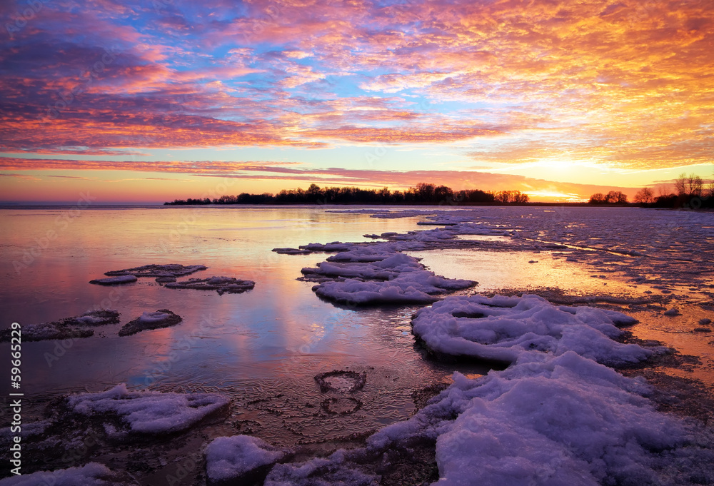 Winter landscape with lake and sunset fiery sky. Composition of