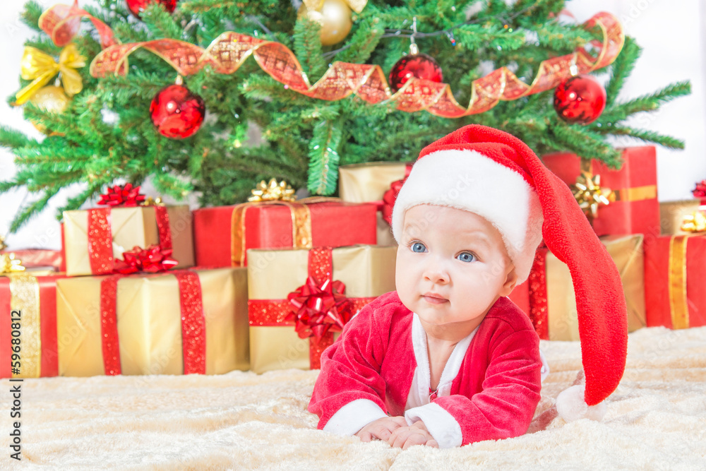child in christmas hat against decorated fir tree and gift boxes child in christmas hat against decorated fir tree and gift boxes