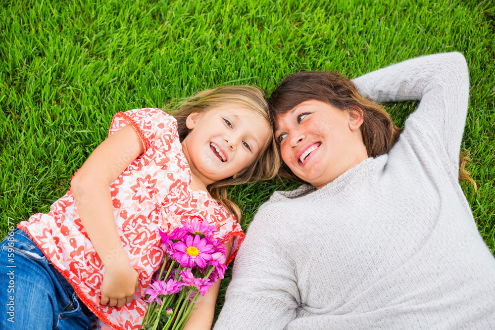 Mother and daughter lying together outside on grass Mother and daughter lying together outside on grass
