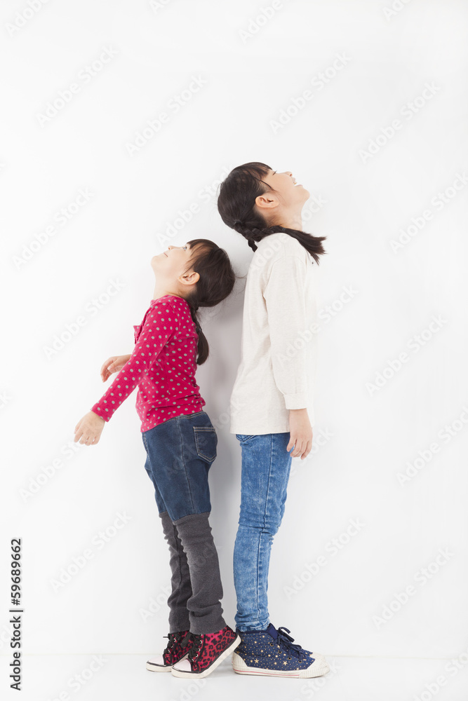 happy little girle standing together and looking up happy little girle standing together and looking up
