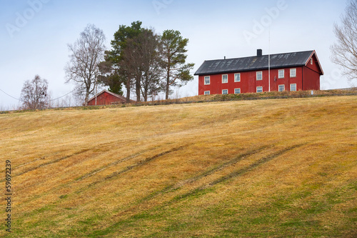 Sprung rural Norwegian landscape with red house and field