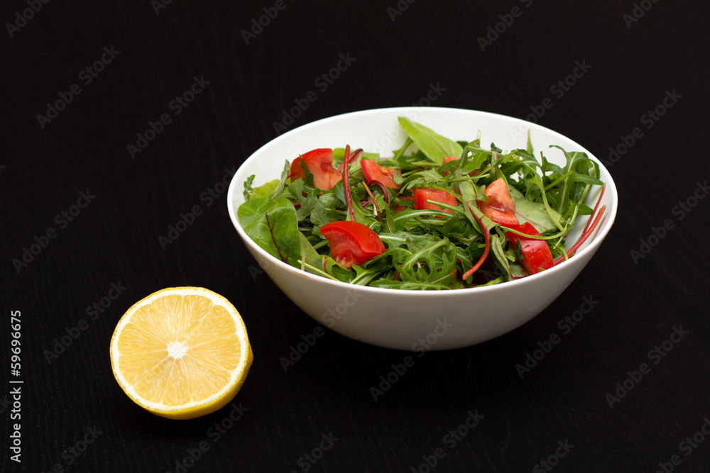 Light salad with tomatoes in white china bowl and lemon Light salad with tomatoes in white china bowl and lemon
