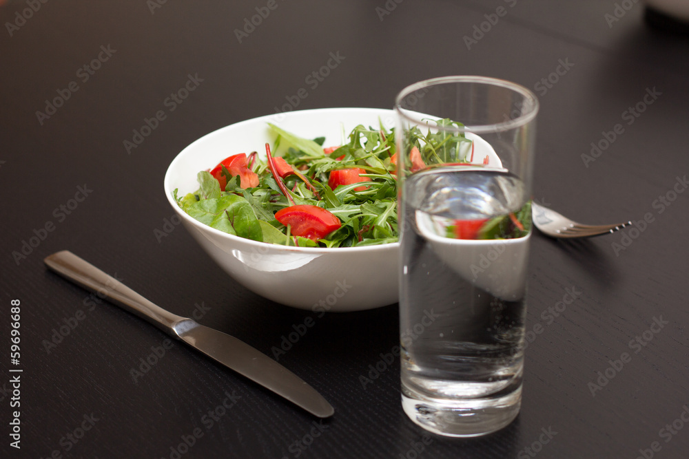 Serving with light salad with tomatoes in white china bowl and a Serving with light salad with tomatoes in white china bowl and a