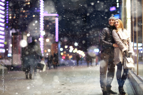 Love man and woman embracing outdoors winter snowfall