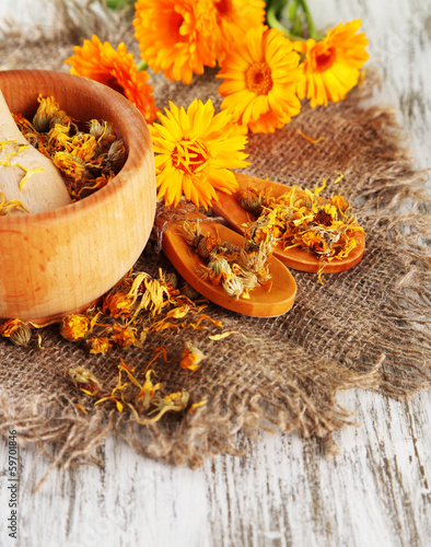 Fototapeta Naklejka Na Ścianę i Meble -  Fresh and dried calendula flowers in mortar on wooden