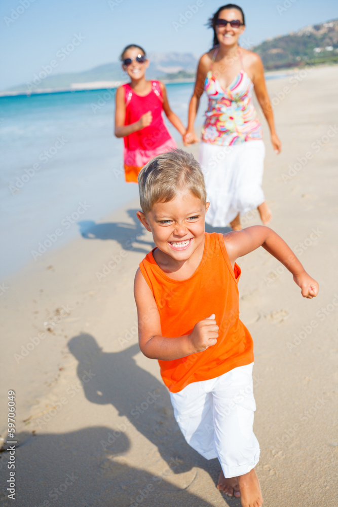 Cute boy with sister and mother on the beach