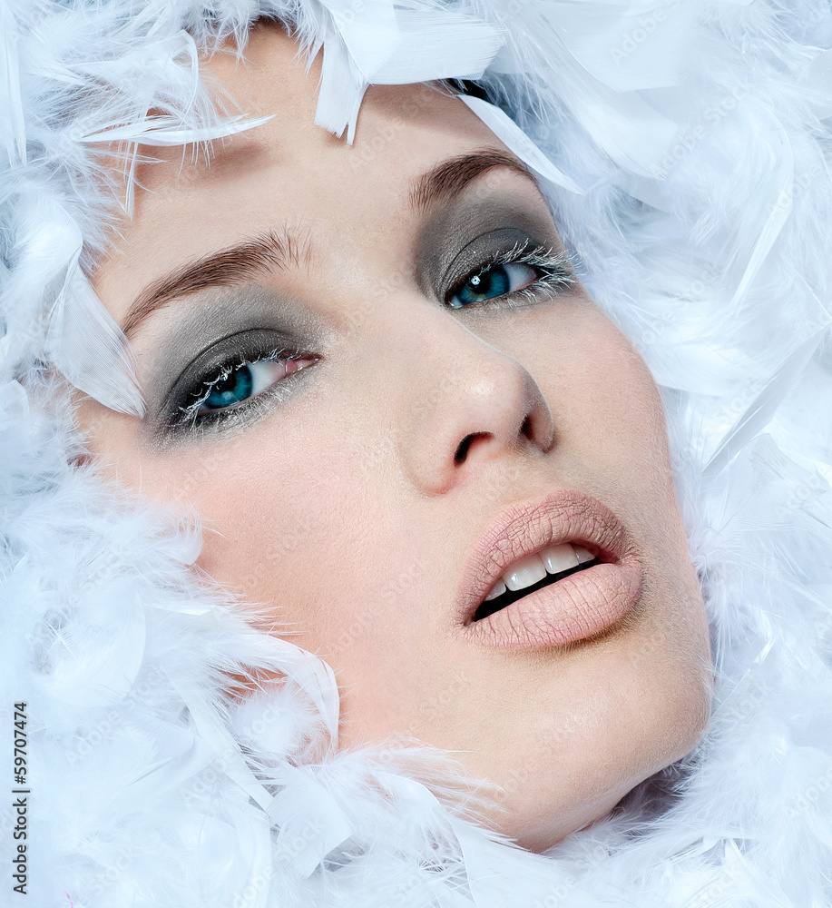 fashionable woman's face surrounded by white feathers