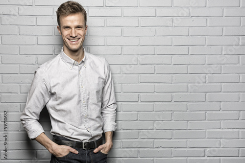 Handsome man standing on Grey wall background, looking camera