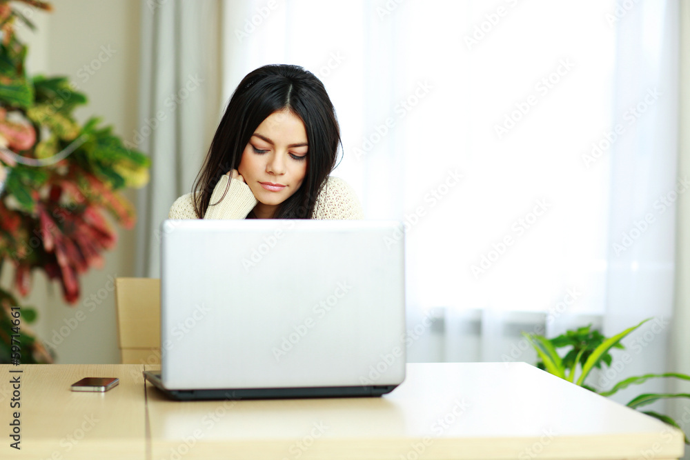 Portrait of a young beautiful woman working on a laptop at home