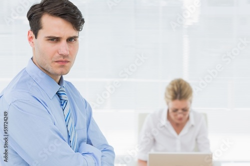 Serious businessman with woman working behind at office