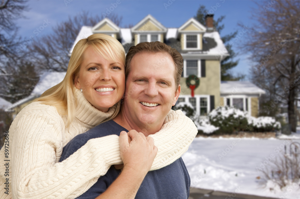 Couple in Front of Beautiful House with Snow on Ground Couple in Front of Beautiful House with Snow on Ground