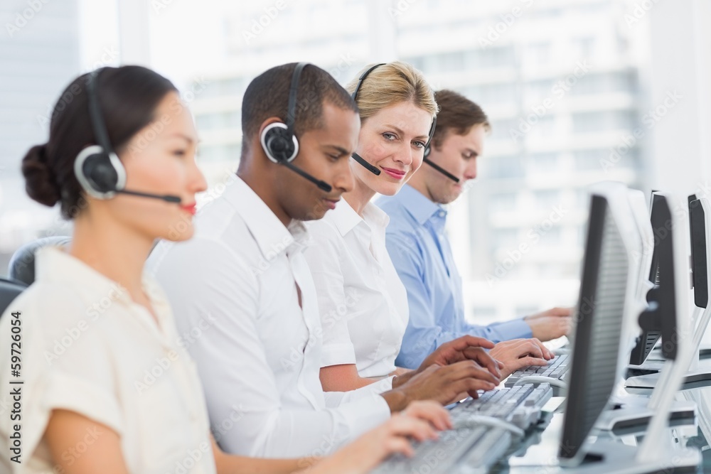 Business colleagues with headsets using computers at desk Business colleagues with headsets using computers at desk