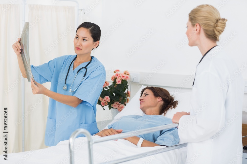 Fototapeta premium Doctors examining x-ray with patient in hospital