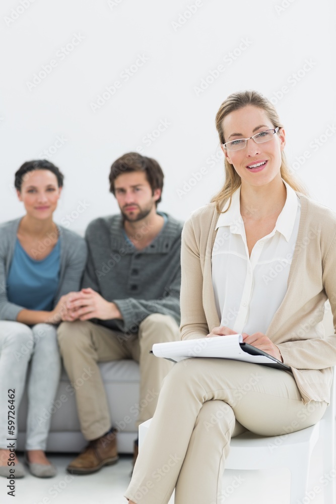 Female financial adviser with young couple in background Female financial adviser with young couple in background