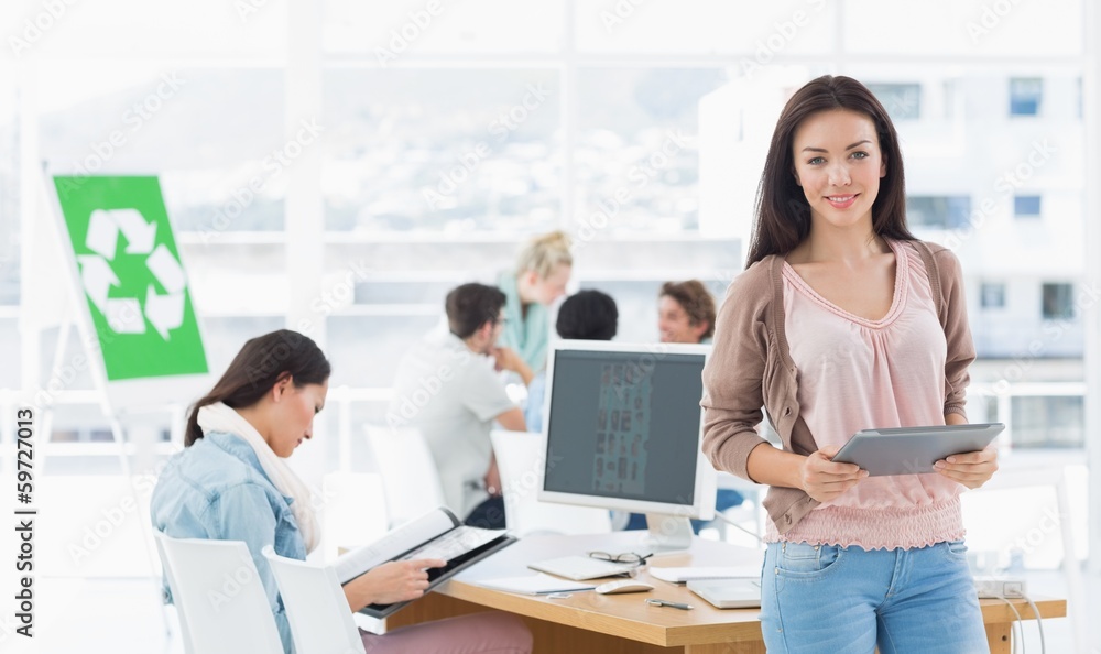 Female artist holding digital tablet with colleagues in backgrou Female artist holding digital tablet with colleagues in backgrou