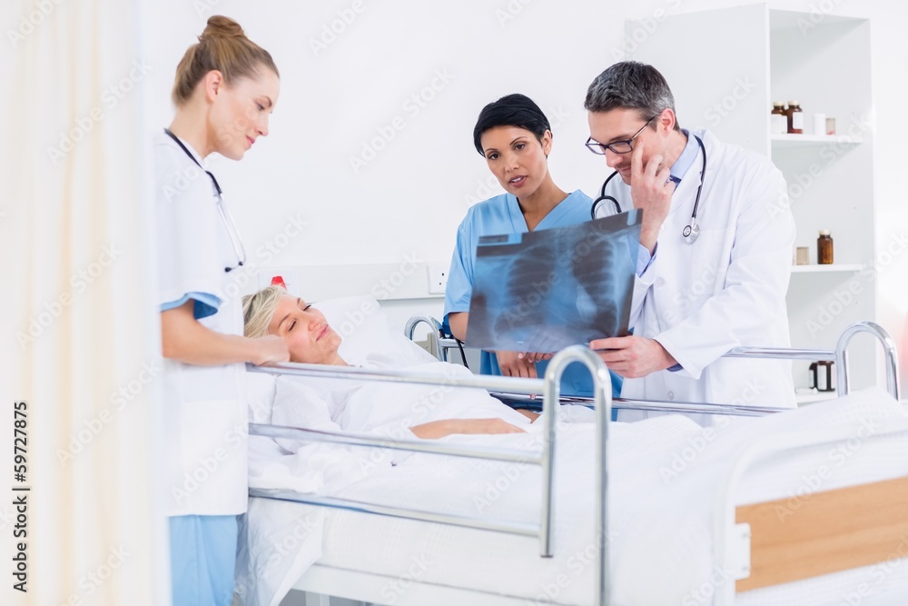 Doctors showing x-ray to patient in bed Doctors showing x-ray to patient in bed