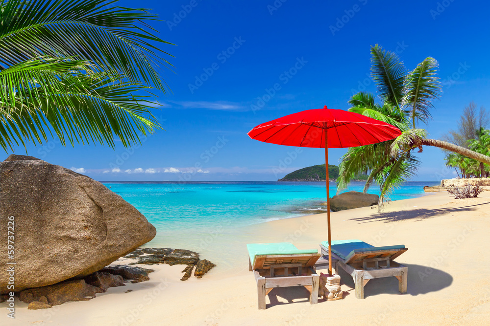 Tropical beach scenery with deck chairs in Thailand
