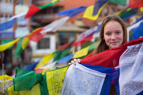 Young girl and Buddhist prayer flags flying.