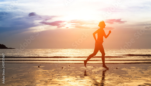 Silhouette of woman jogger at sunset on the seashore