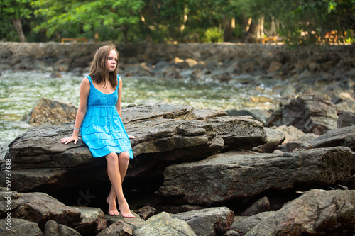 Girl in a blue dress in the rocks of the coast. © De Visu