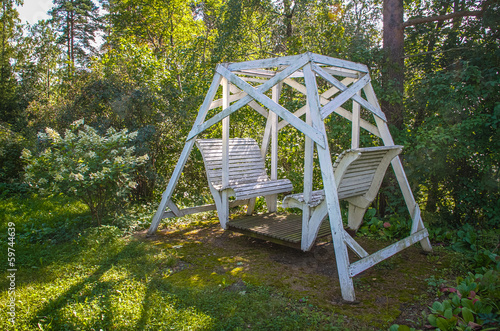 White swing bench in a summer country garden