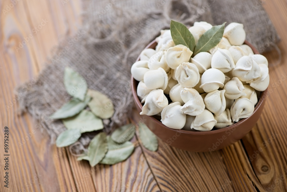 Raw pelmeni or meat dumplings with bay leaves, horizontal shot Raw pelmeni or meat dumplings with bay leaves, horizontal shot