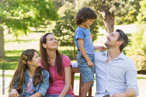 Couple with young kids sitting on park bench