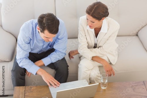 Business partners working together on laptop sitting on sofa