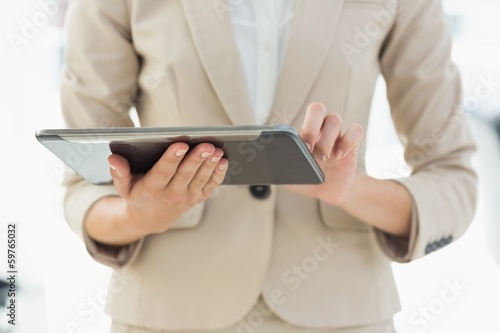 Mid section of a businesswoman using digital tablet