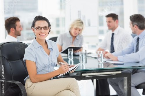 Businesswoman holding clipboard with colleagues discussing in of