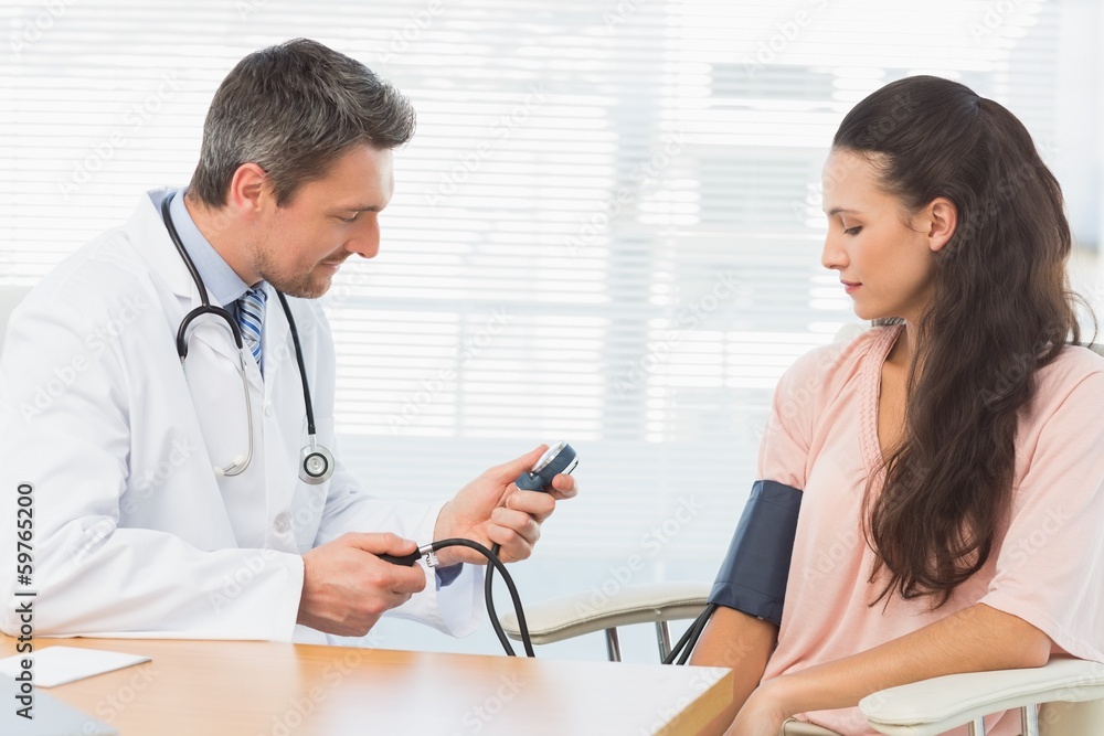 Male doctor checking blood pressure of a woman Male doctor checking blood pressure of a woman