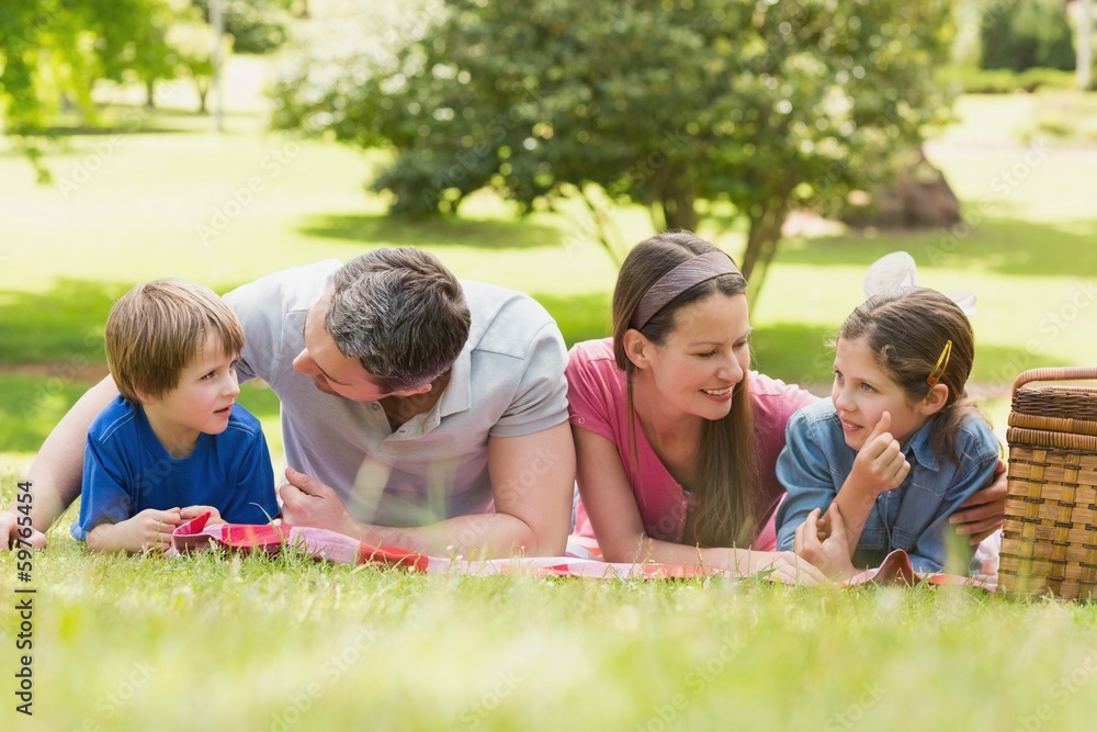 Smiling couple with young kids lying on grass in park Smiling couple with young kids lying on grass in park