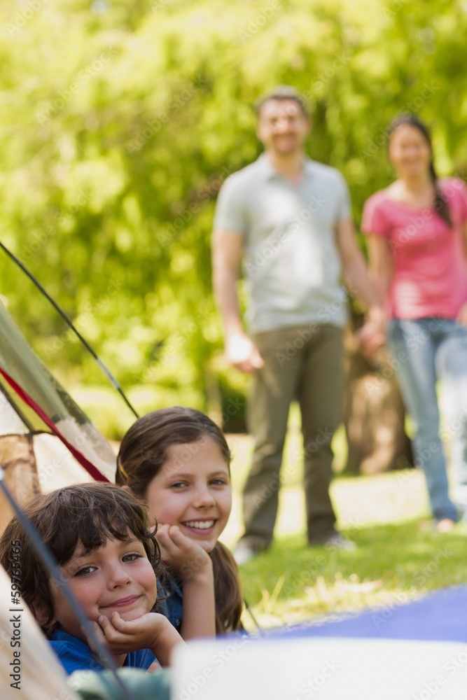 Kids in tent with couple in background at park Kids in tent with couple in background at park