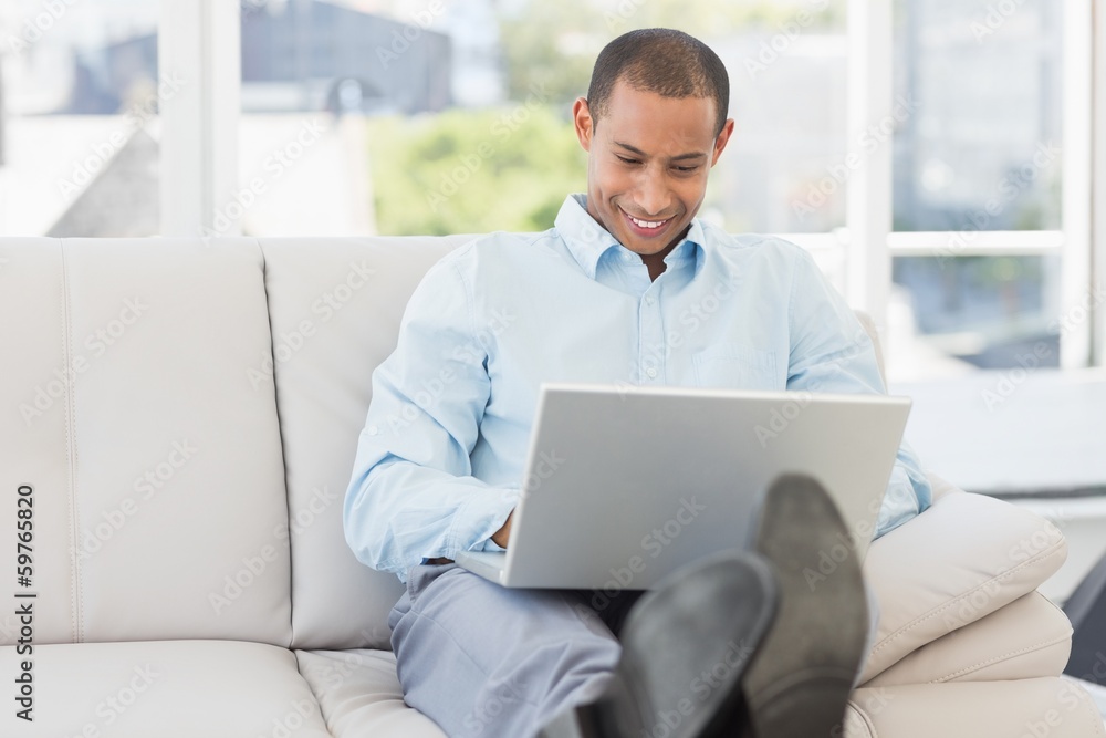 Happy businessman using laptop with his feet up Happy businessman using laptop with his feet up