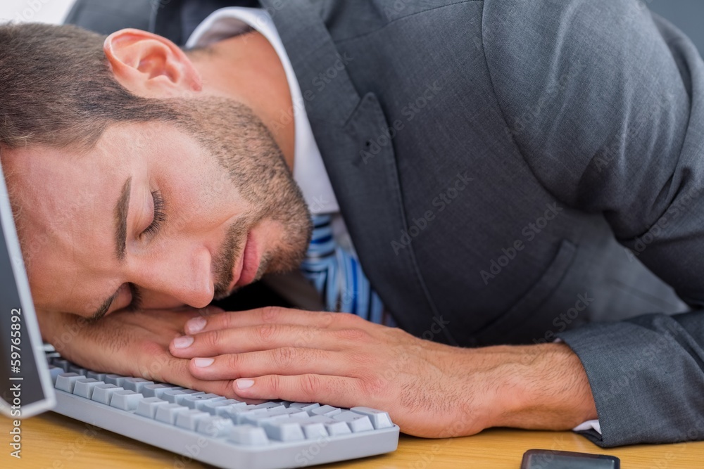 Businessman resting with head over keyboard at desk Businessman resting with head over keyboard at desk