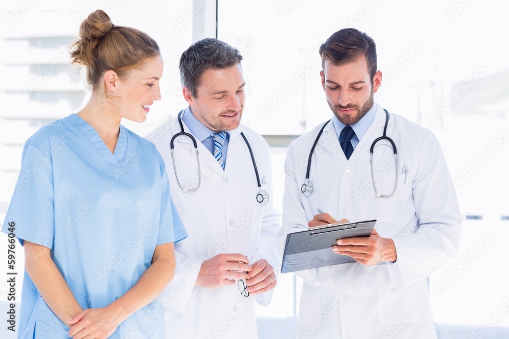 Doctors and female surgeon reading medical reports Doctors and female surgeon reading medical reports