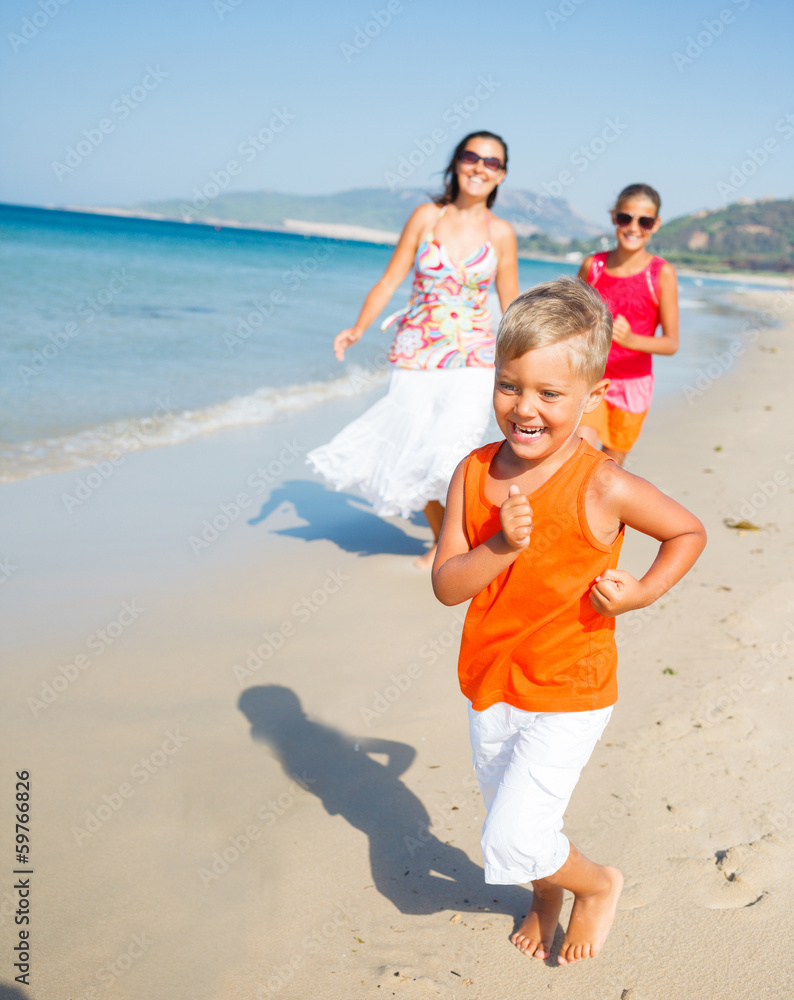 Cute boy with sister and mother on the beach