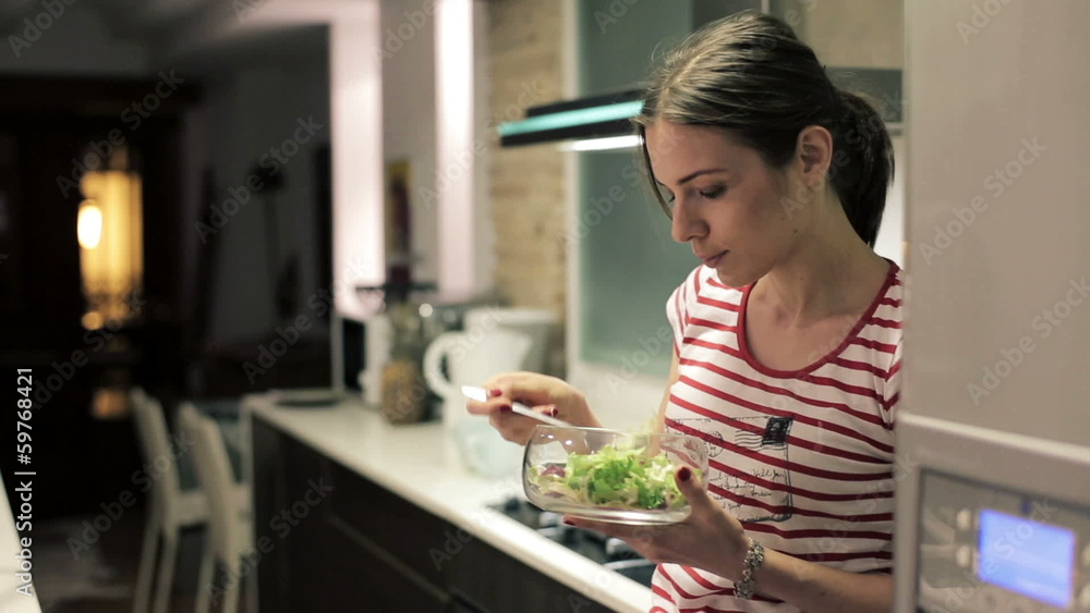 Young attractive woman eating salad in the kitchen