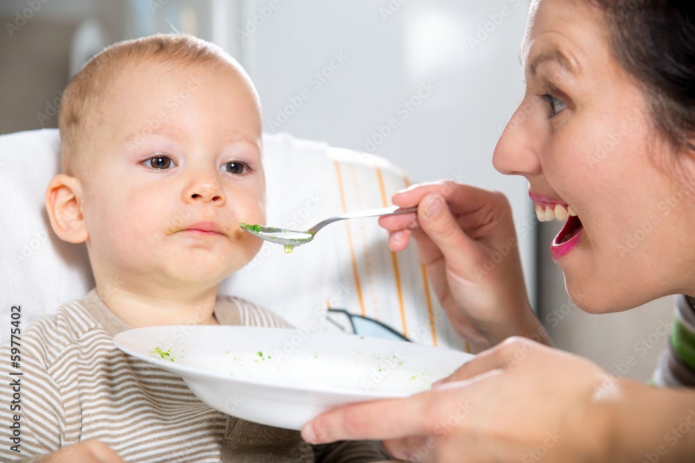 Mother feeding hungry baby in the highchair indoors Stock Photo Adobe
